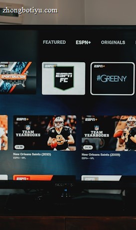 A television screen displaying the ESPN+ streaming interface with various sports-related shows and categories. The screen includes sections such as 'Browse by Shows' and 'Best of Drew Brees' with thumbnails of sports programs featuring athletes in action and analysts.